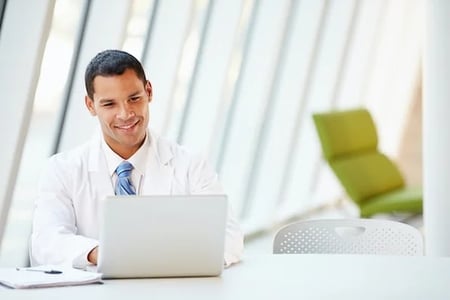 businessman using a laptop in an office to find a video content management system